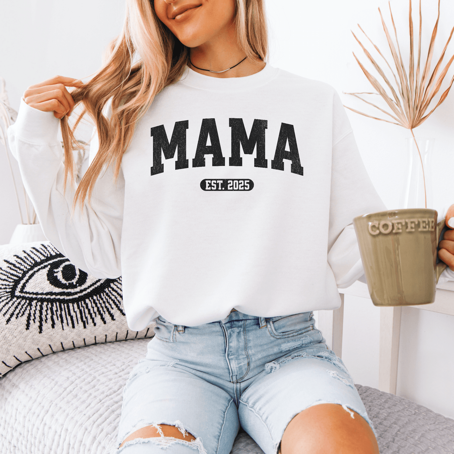 Woman sitting in white crewneck wearing Custom Mama EST Year Sweatshirt with EST 2025 print holding coffee