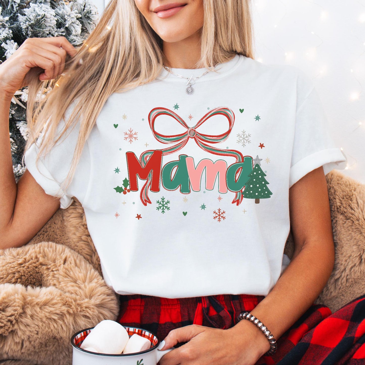 Woman wearing Custom Preppy Christmas Family Shirt white tee with pink and red mama design holiday bow tree snowflakes holding mug