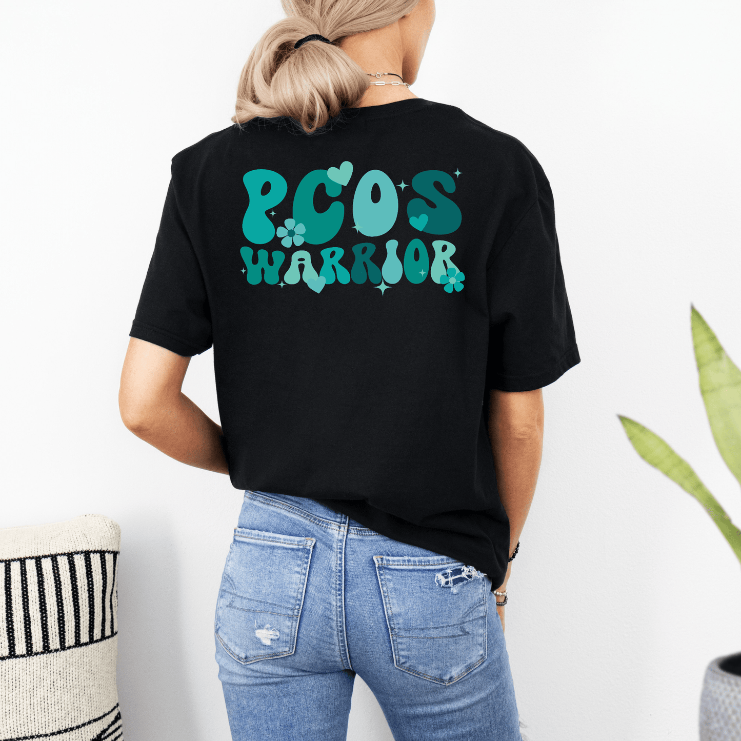 Back view of woman wearing Maddy and George Designs black Polycystic Ovary Syndrome Awareness Shirt with teal PCOS Warrior graphic