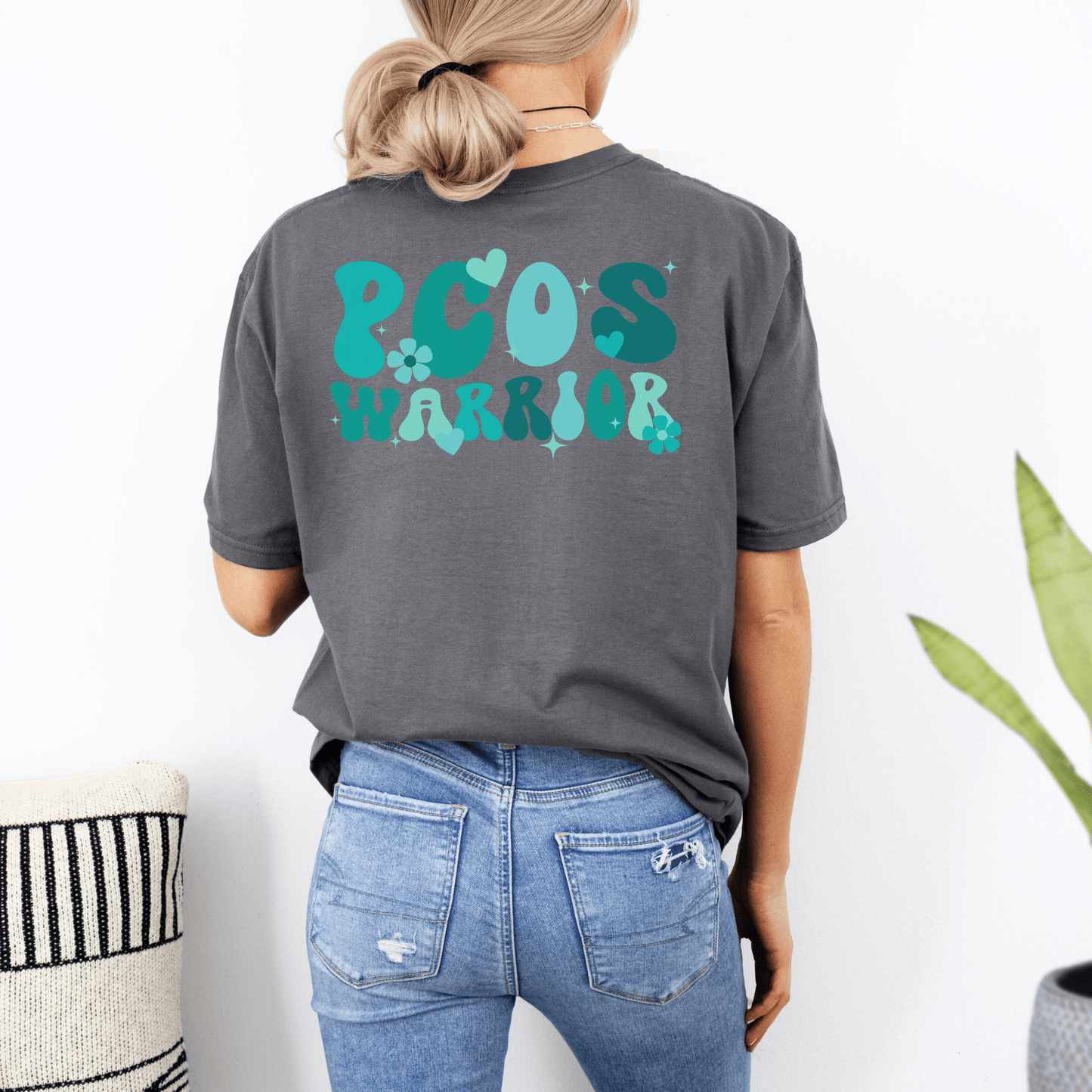 Woman wearing dark gray Polycystic Ovary Syndrome Awareness Shirt with teal PCOS warrior design on back