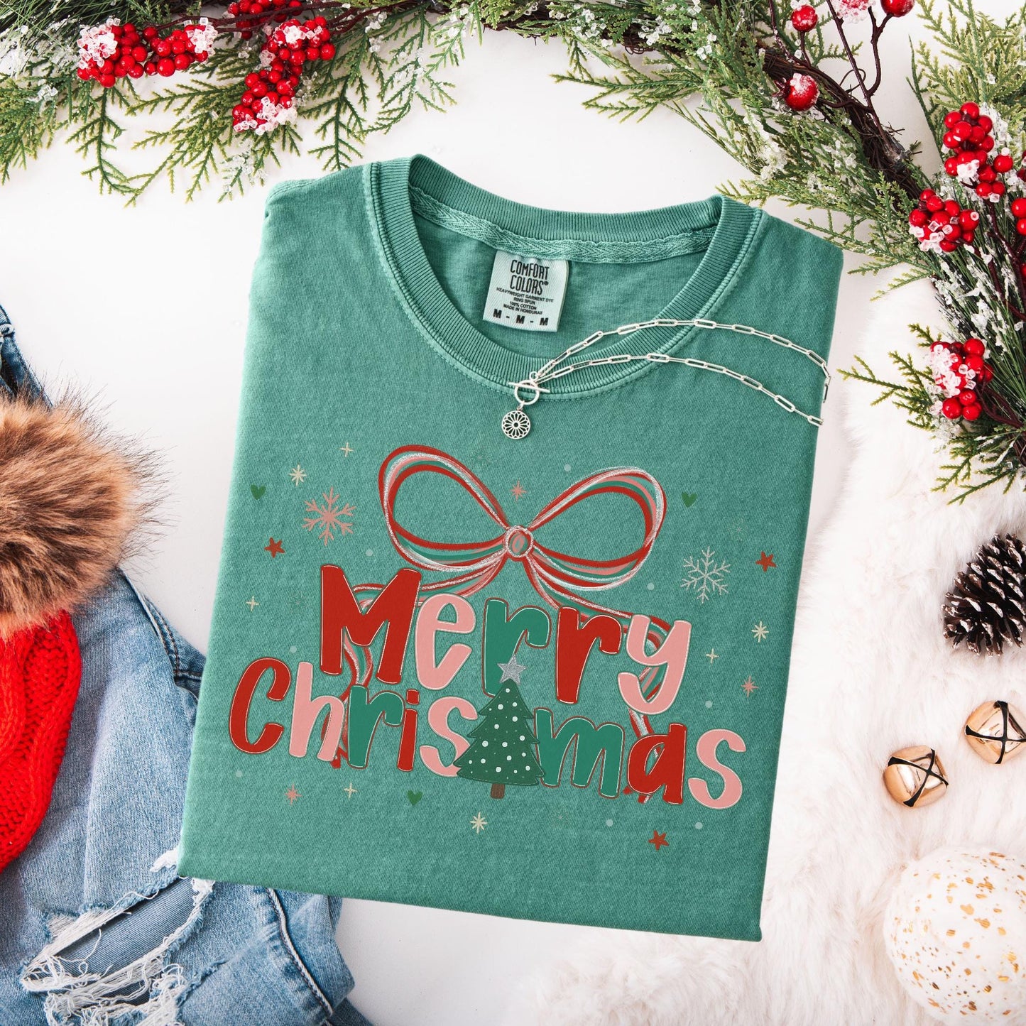 Preppy Merry Christmas Shirt green folded tee with bow and tree graphic and pendant necklace styled with winter props