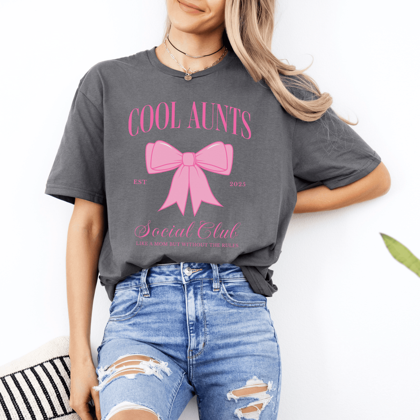 Woman wearing gray tee with pink bow and script text Custom Cool Aunts Social Club Shirt