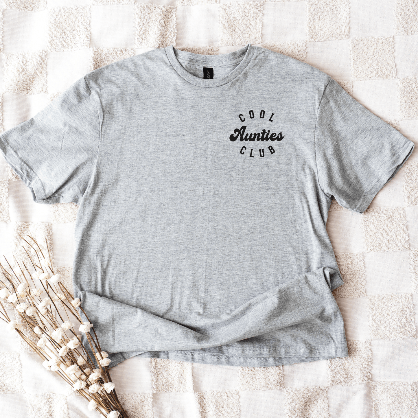 Gray crewneck tee shirt laid flat with small black chest print reading Cool Aunties Club Shirt . by Maddy and George Designs