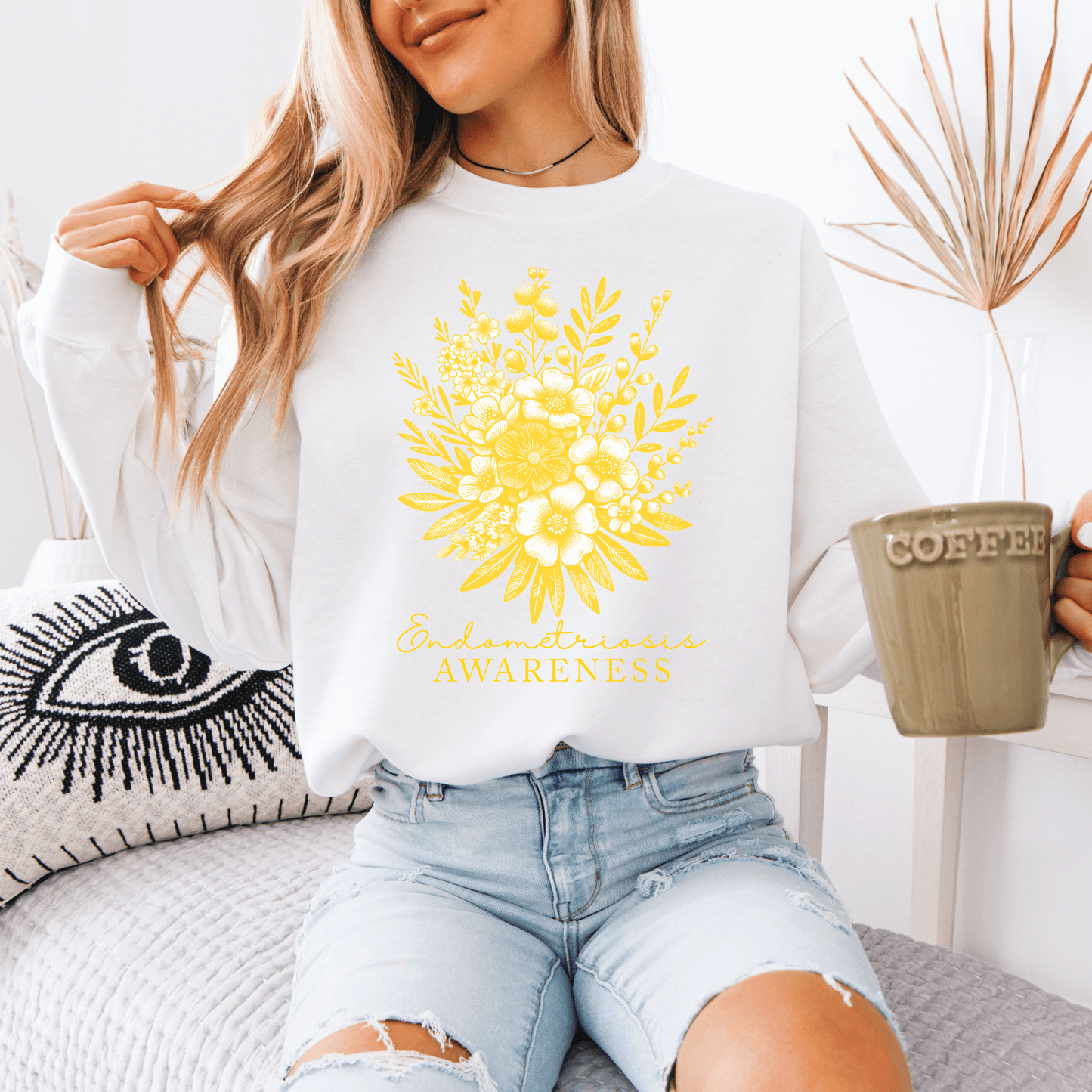 Woman wearing a white Floral Endometriosis Awareness Sweatshirt with yellow floral bouquet print holding a coffee mug