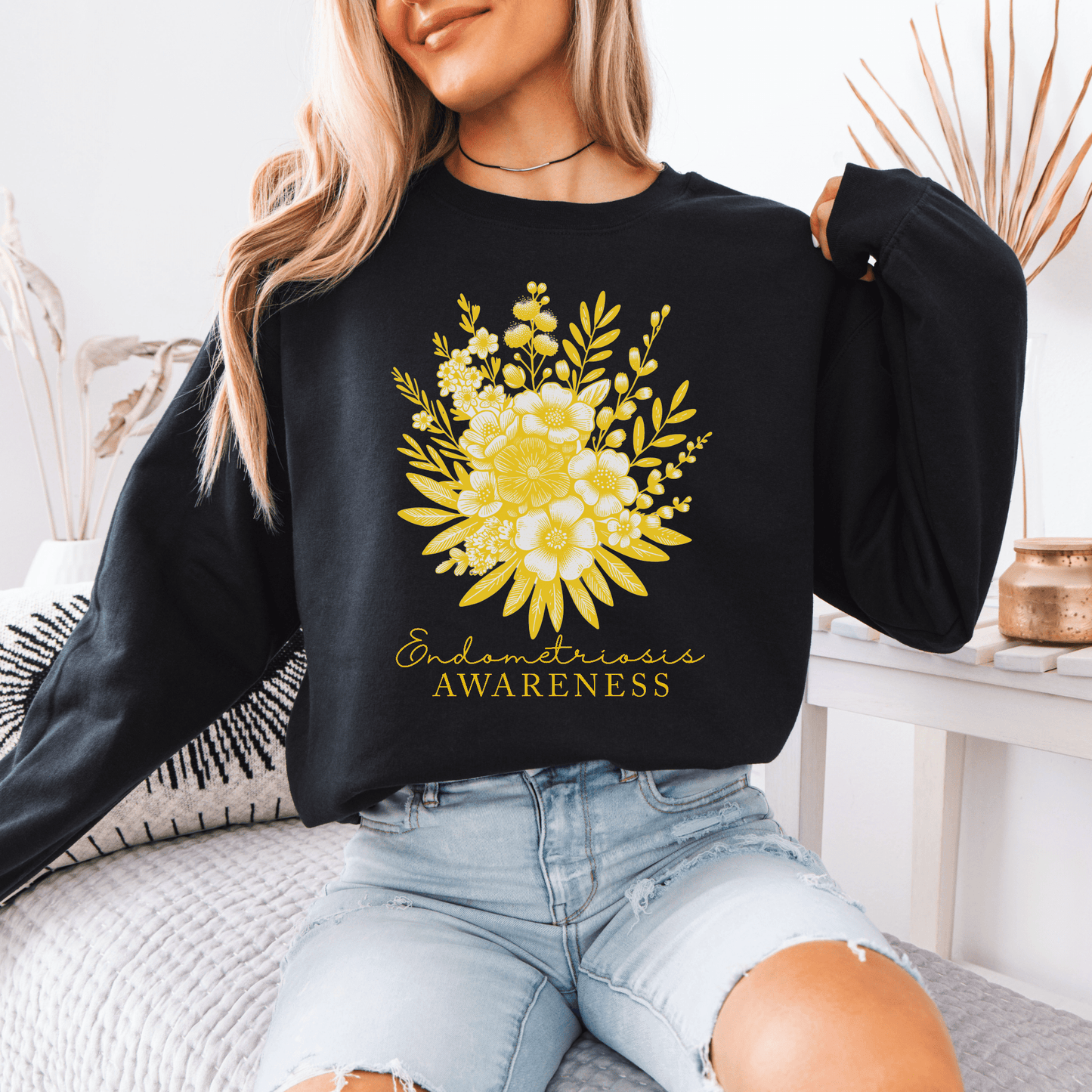 Model wearing Floral Endometriosis Awareness Sweatshirt . Black crewneck with yellow floral bouquet print and awareness text