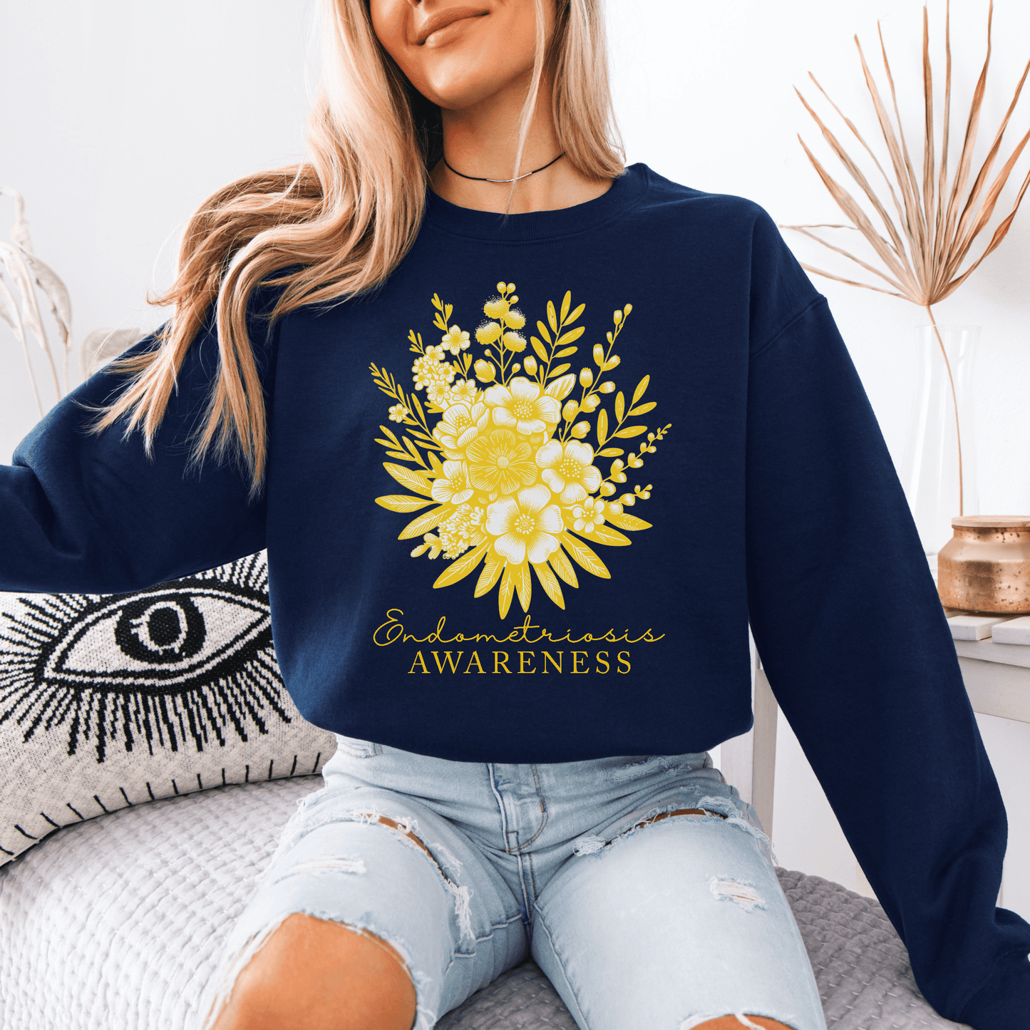 Woman wearing navy Floral Endometriosis Awareness Sweatshirt with yellow floral bouquet design and distressed jeans