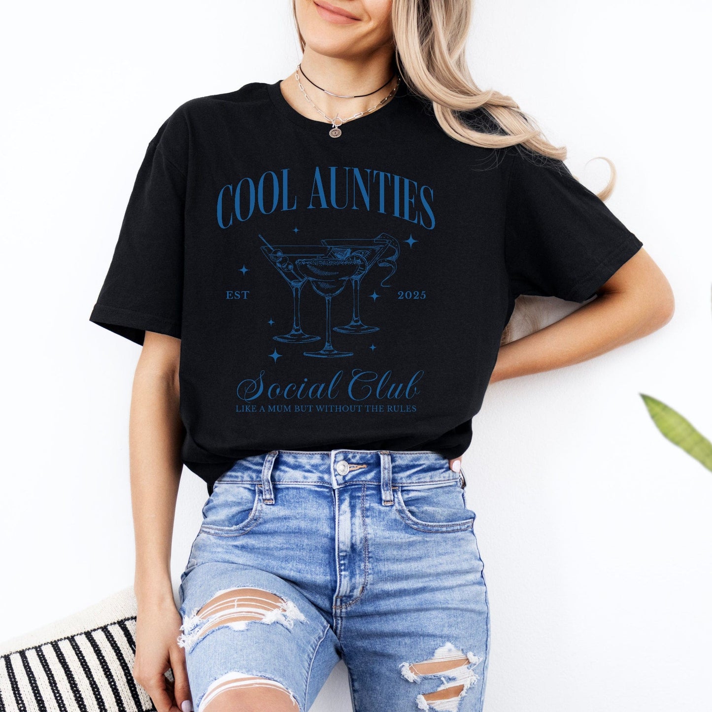 Model wearing black Cool Aunties Social Club Shirt . blue martini glass design with casual ripped jeans