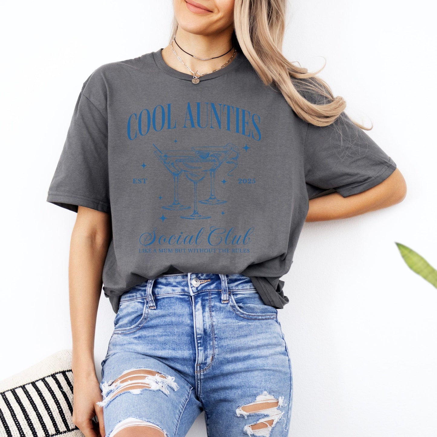 Model wearing Maddy and George Designs gray Cool Aunties Social Club Shirt . with blue martini graphic and ripped jeans