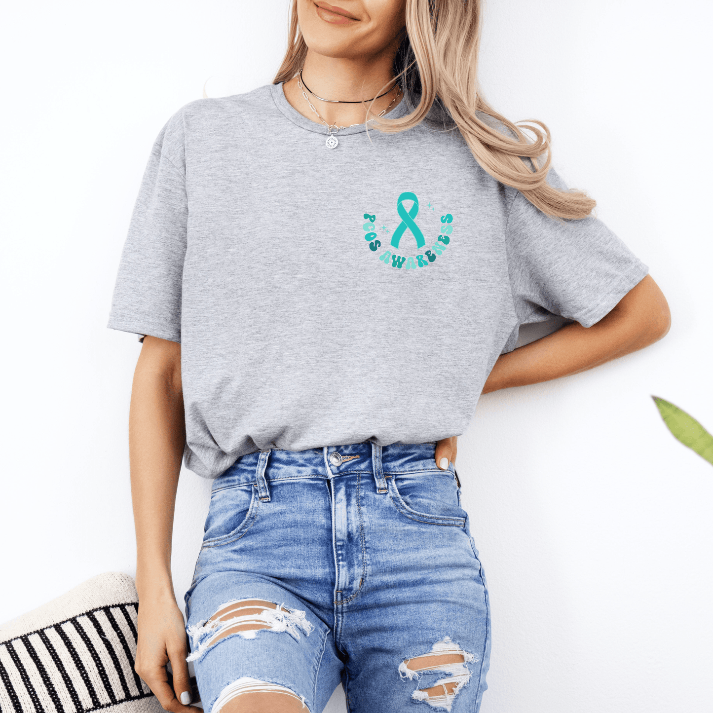 PCOS Awareness Shirt gray tee with teal ribbon chest print by Maddy and George Designs modeled with ripped jeans