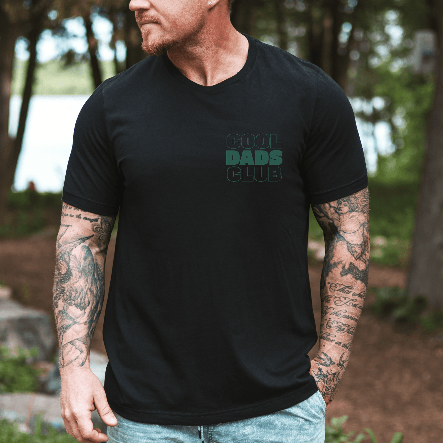 Black graphic tee Cool Dads Club Shirt | New Dad Gift with small left chest logo worn by tattooed man