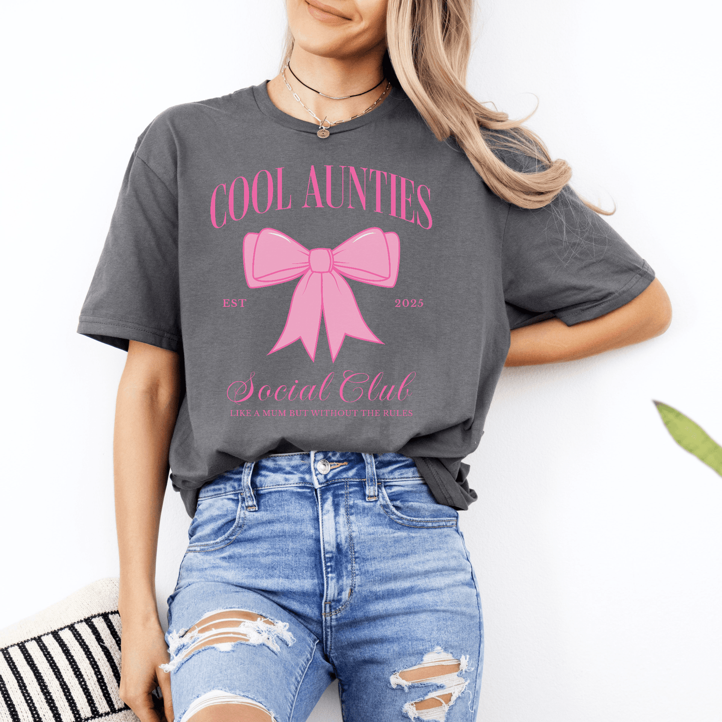 Woman wearing Custom Cool Aunties Club Shirt gray tee with pink bow graphic styled with ripped jeans