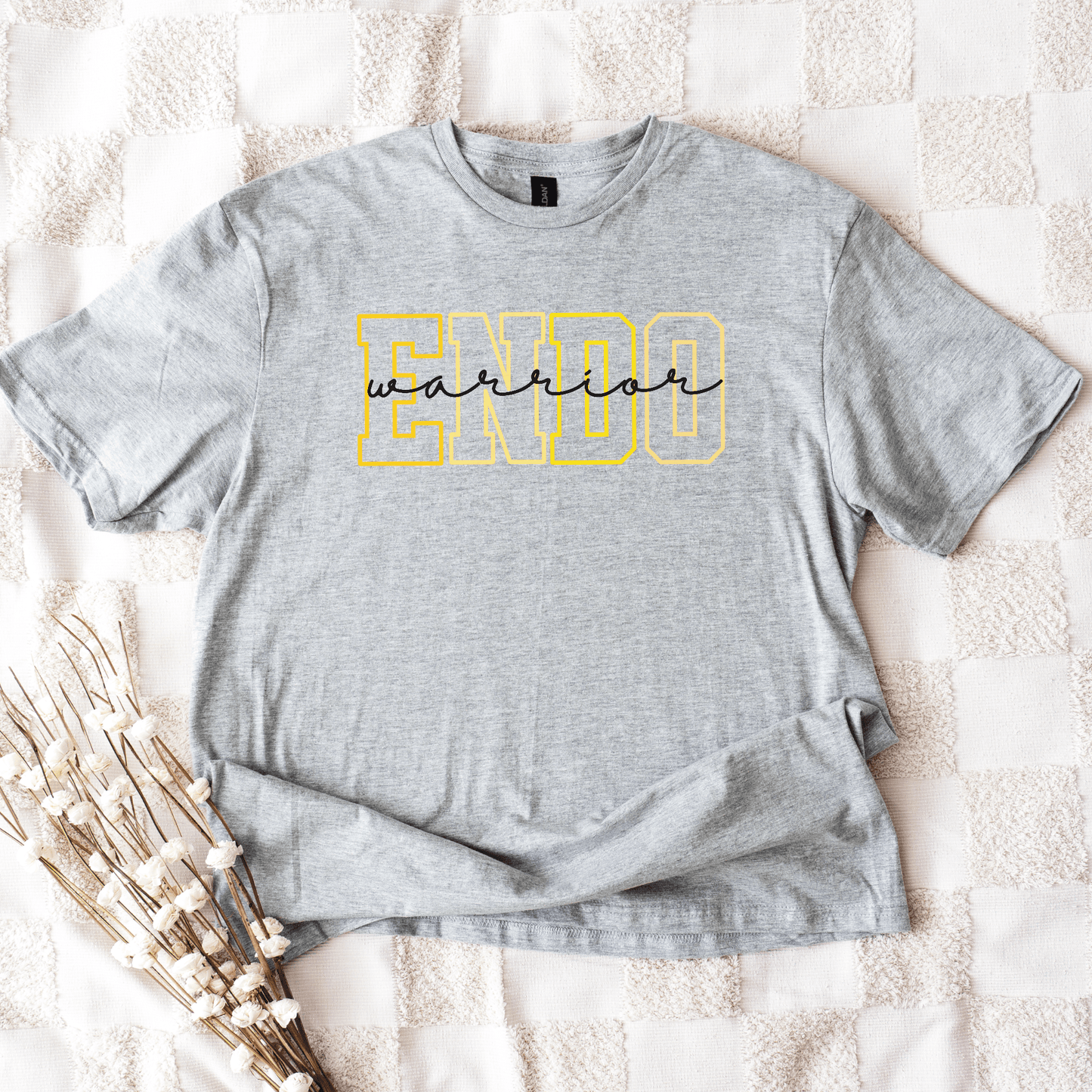 Endometriosis Awareness Shirt | Gift For Endo Warrior. Gray tee with yellow ENDO and black warrior script resting on blanket