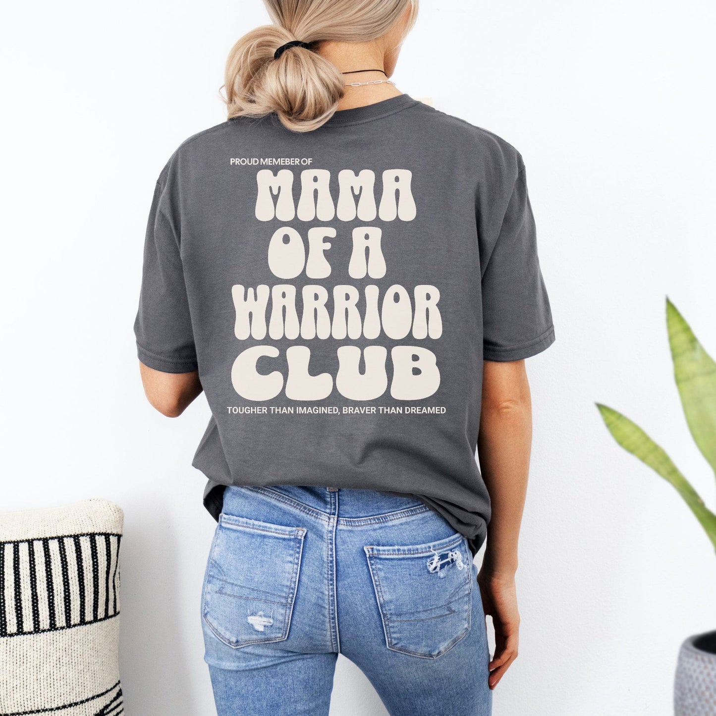 Rear view of woman wearing gray Mama of a Warrior Club Shirt by Maddy and George Designs with cream retro text
