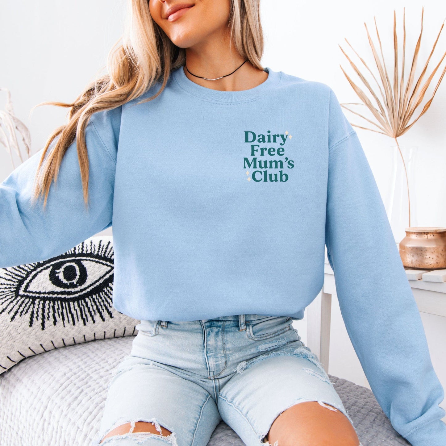 Light blue Dairy Free Mum’s Club Sweatshirt on seated model with ripped jeans showing small left chest logo