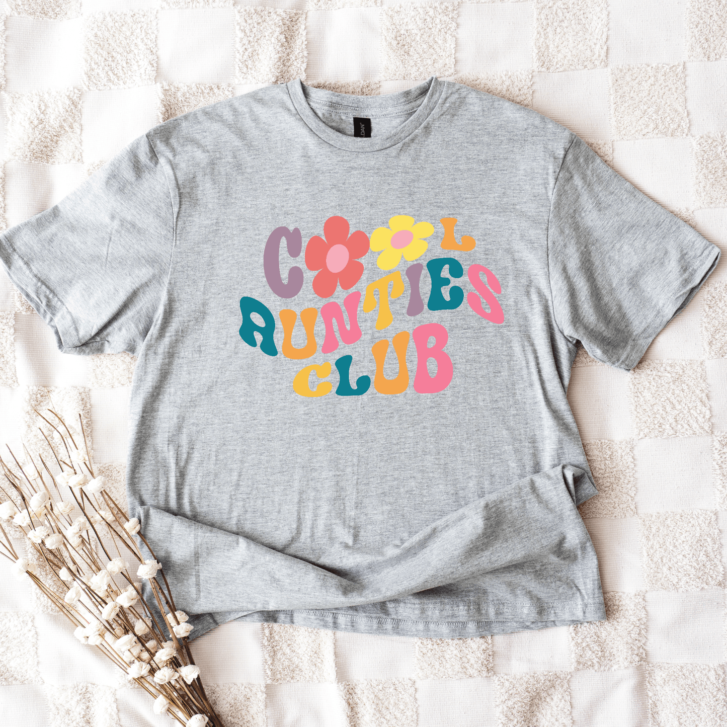 Gray unisex tee laid flat with colorful 70s floral lettering reading Retro Cool Aunties Club Shirt by Maddy and George Designs