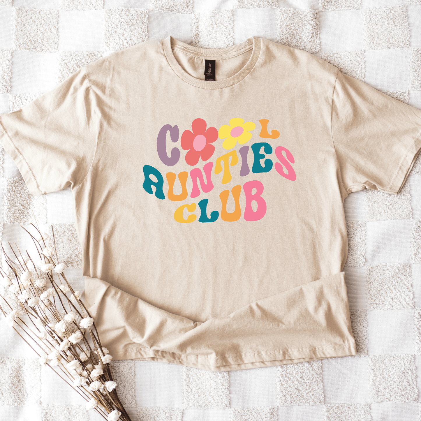 Beige cotton t shirt flatlay with colorful 70s flower lettering reading Retro Cool Aunties Club Shirt from Maddy and George