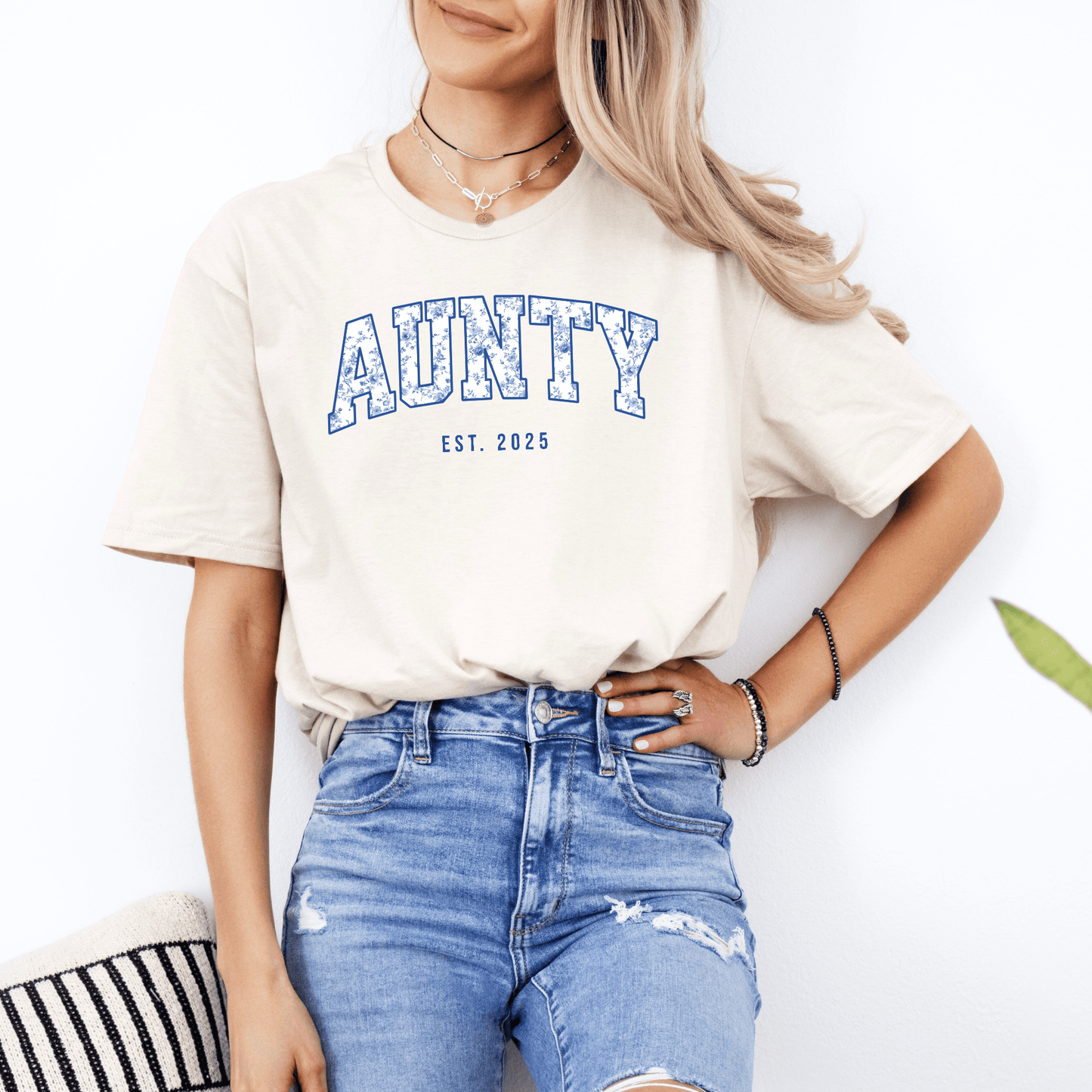 Woman wearing Maddy and George Designs Custom Aunty Est. Year Shirt cream tee with blue collegiate AUNTY print