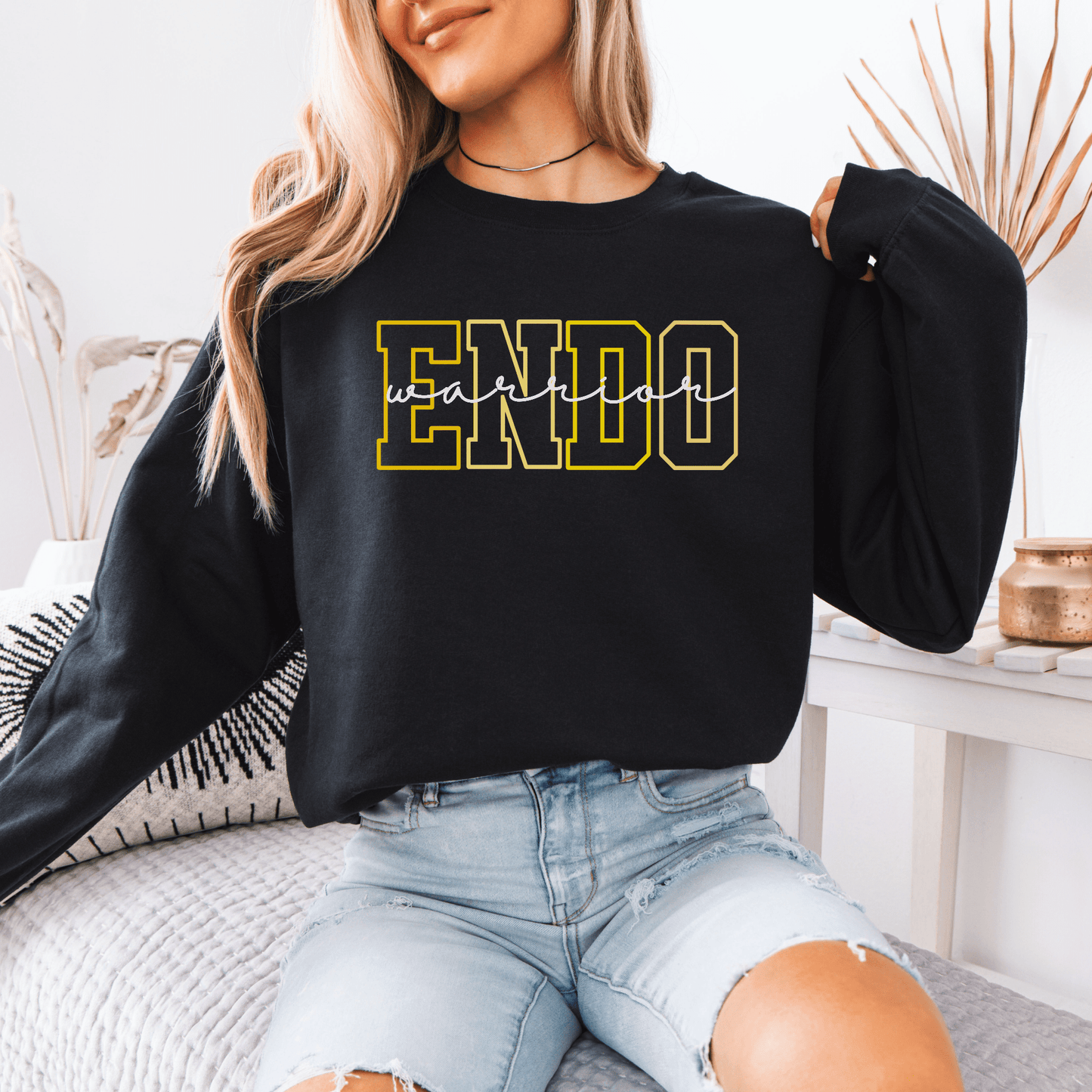 Woman wearing black Endometriosis Warrior Sweatshirt . Maddy and George Designs crewneck with yellow outlined ENDO logo