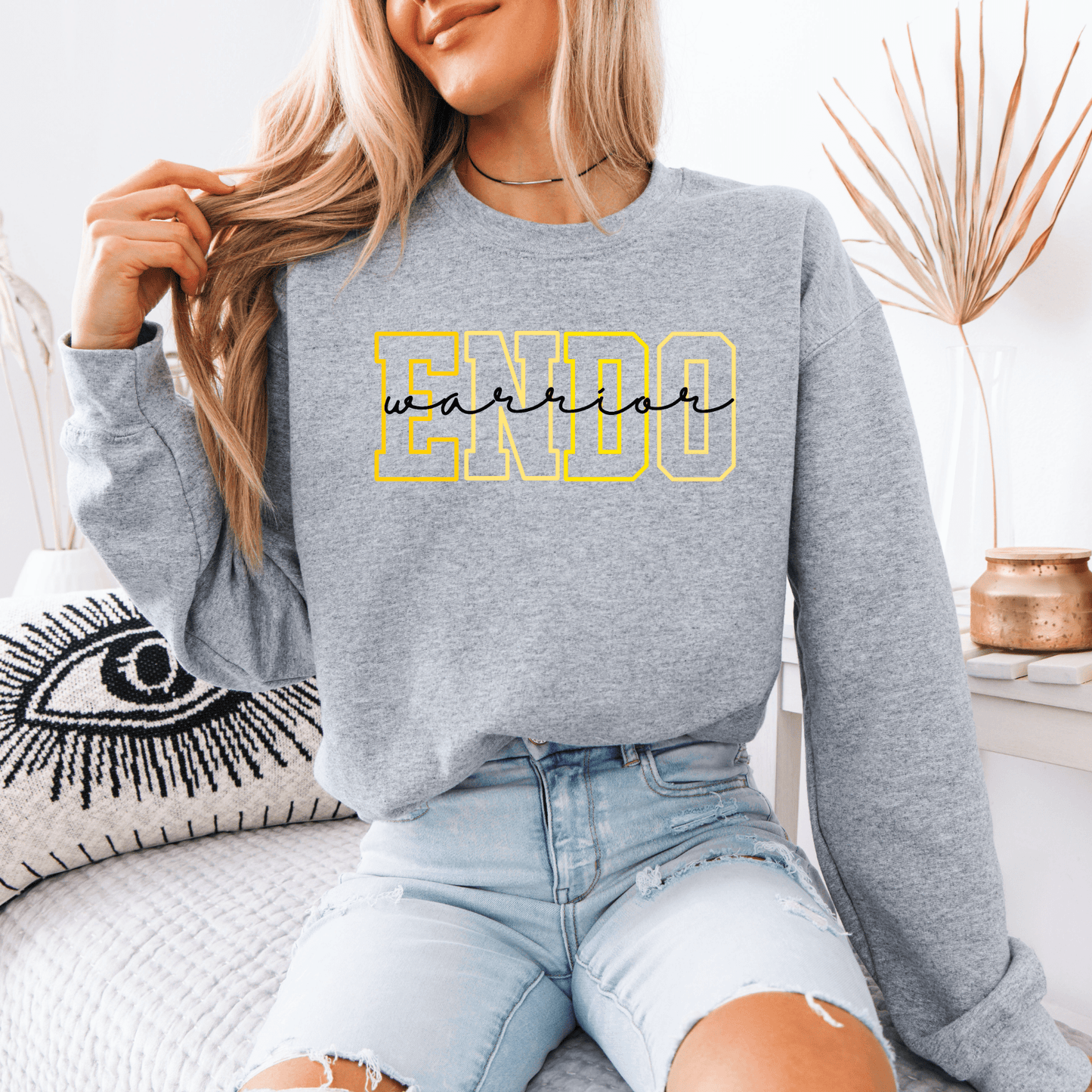 Woman wearing gray crewneck sweatshirt with yellow outlined ENDO letters and script, Endometriosis Warrior Sweatshirt .