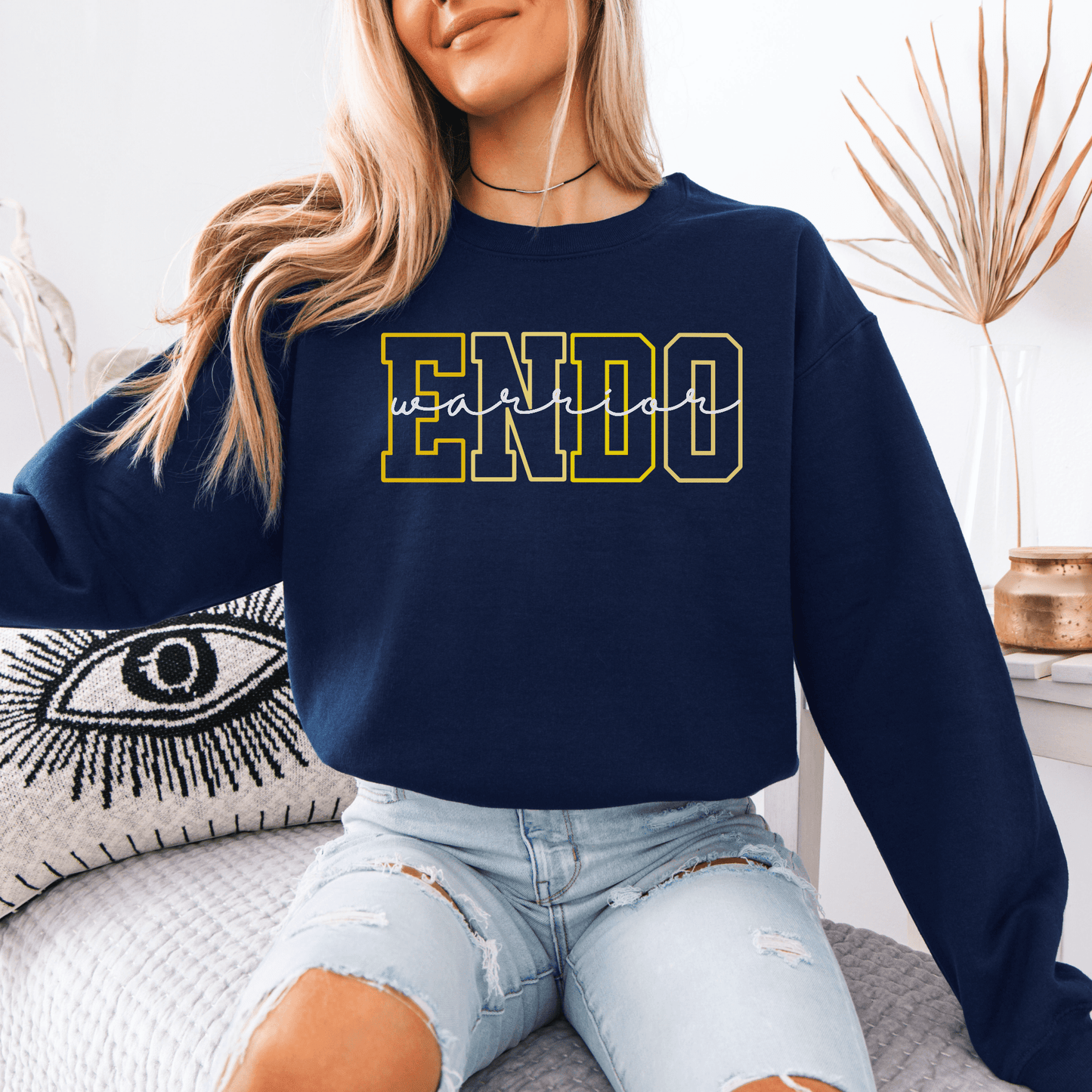 Model wearing navy Endometriosis Warrior Sweatshirt with bold yellow ENDO varsity print over jeans