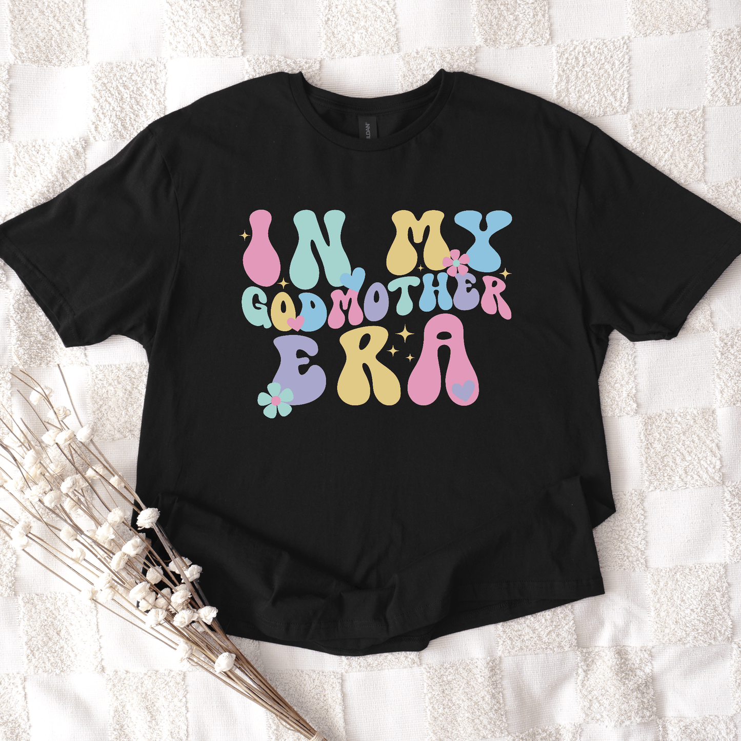 Black tee featuring retro pastel bubble letters reading In My Godmother Era with floral accents Godmother Announcement Shirt