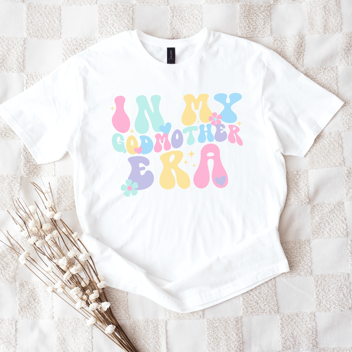 White t shirt with pastel groovy bubble letters reading In My Godmother Era and floral accents Godmother Announcement Shirt