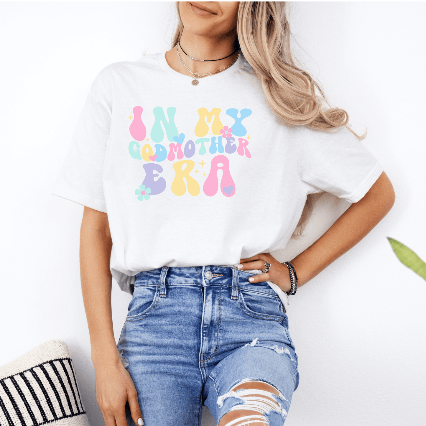 Woman wearing Maddy and George Designs Godmother Announcement Shirt white tee with pastel retro bubble text for pregnancy reveal
