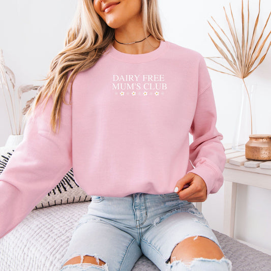 Woman wearing pink sweatshirt with Dairy Free Mum's Club text seated in ripped jeans lifestyle photo CMPA & Allergy Awareness Gift