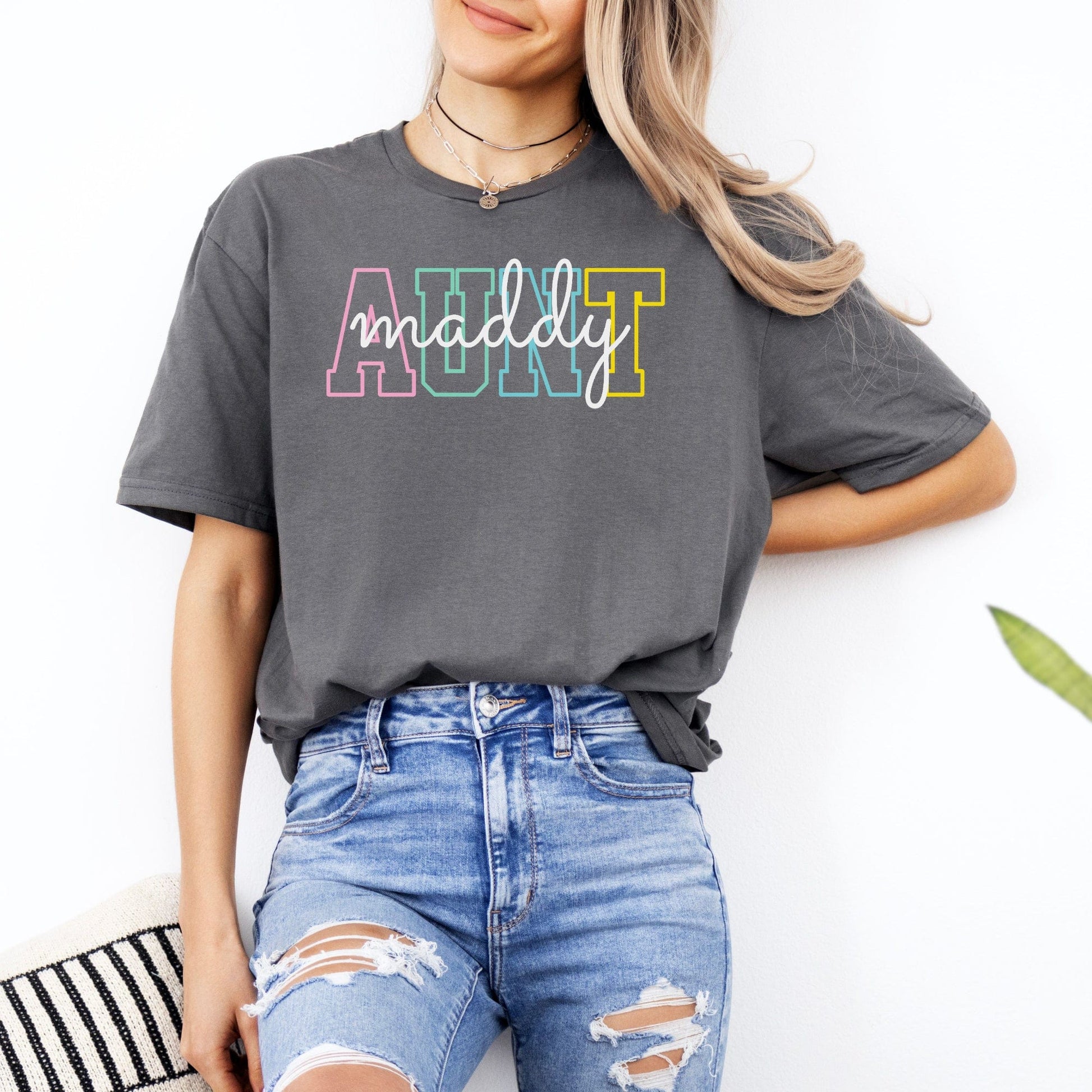 Woman wearing gray Custom Aunt Shirt with multicolor block AUNT letters and white cursive maddy name