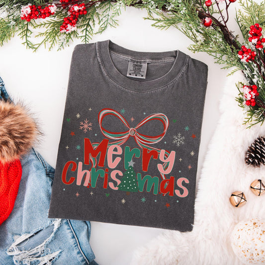Preppy Merry Christmas Shirt folded charcoal gray tee with red bow and Christmas tree graphic surrounded by holiday decor