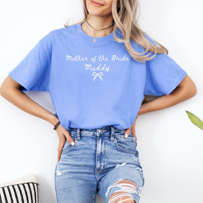 Woman wearing light blue Custom Mother of the Bride Shirt with white script name Maddy and bow over ripped high waisted jeans
