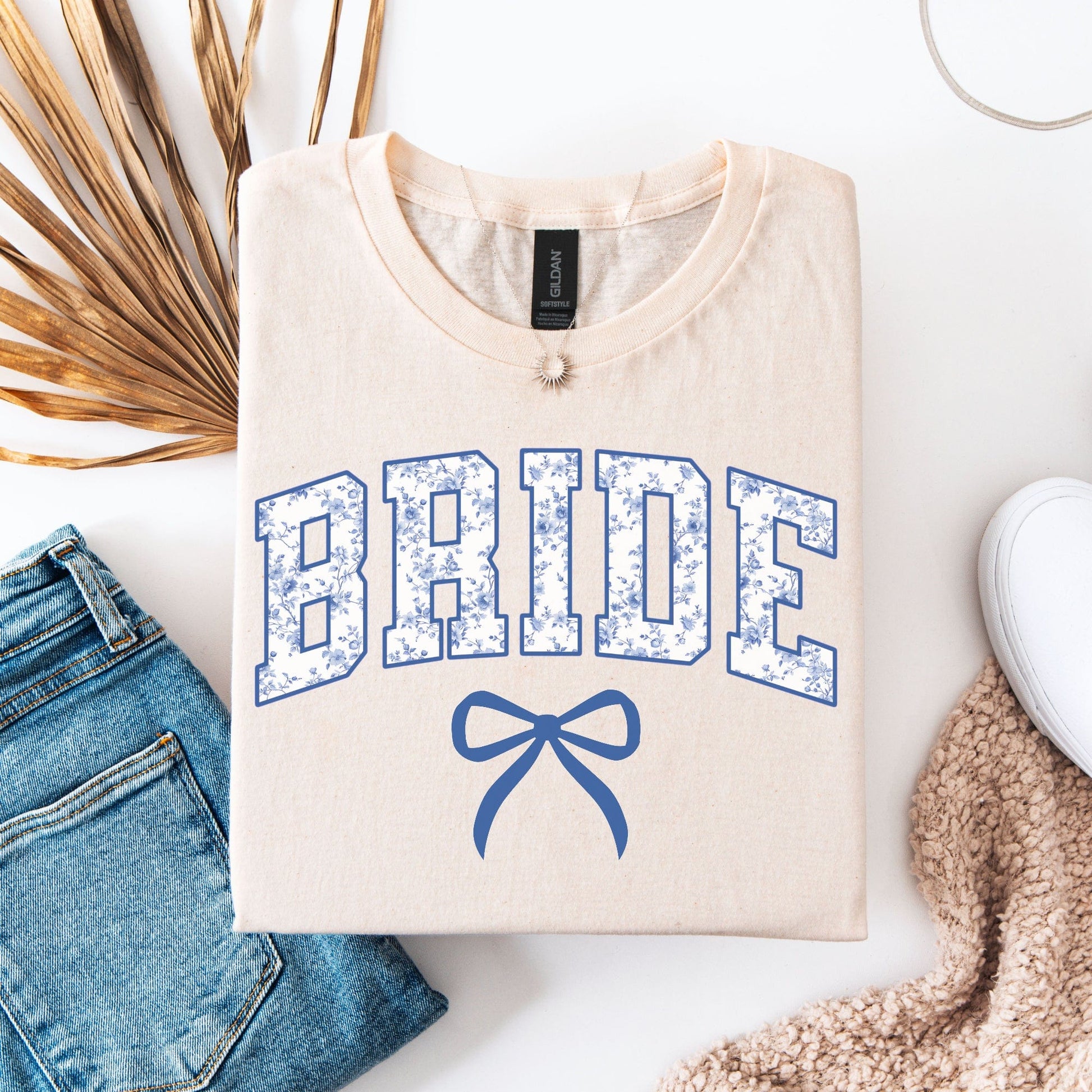 Chinoiserie Bride T-Shirt . cream folded tee with blue floral collegiate BRIDE lettering and bow styled with jeans and sneaker