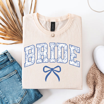 Chinoiserie Bride T-Shirt . cream folded tee with blue floral collegiate BRIDE lettering and bow styled with jeans and sneaker