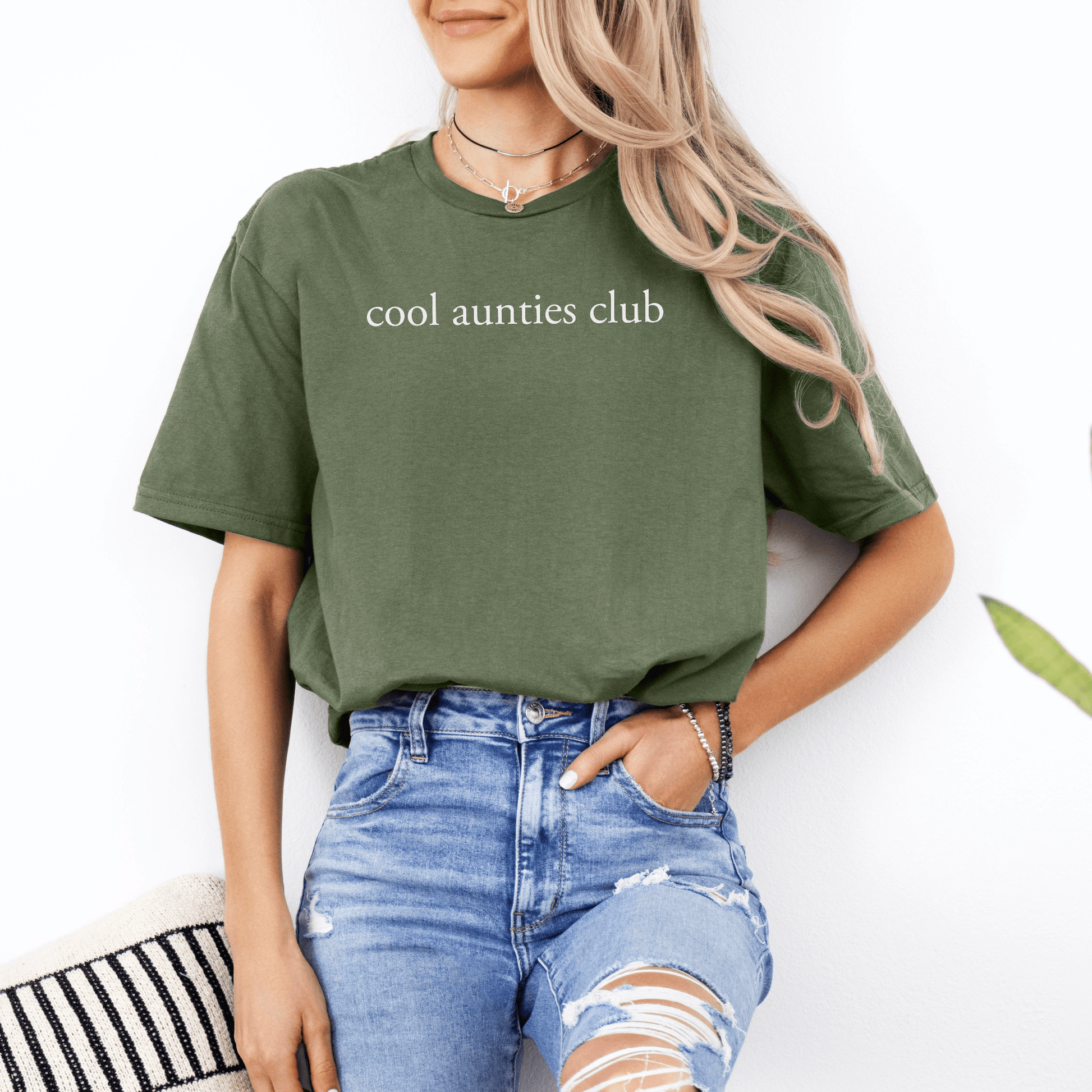 New Auntie Pregnancy Announcement Gift olive green t shirt saying cool aunties club worn by woman with ripped jeans