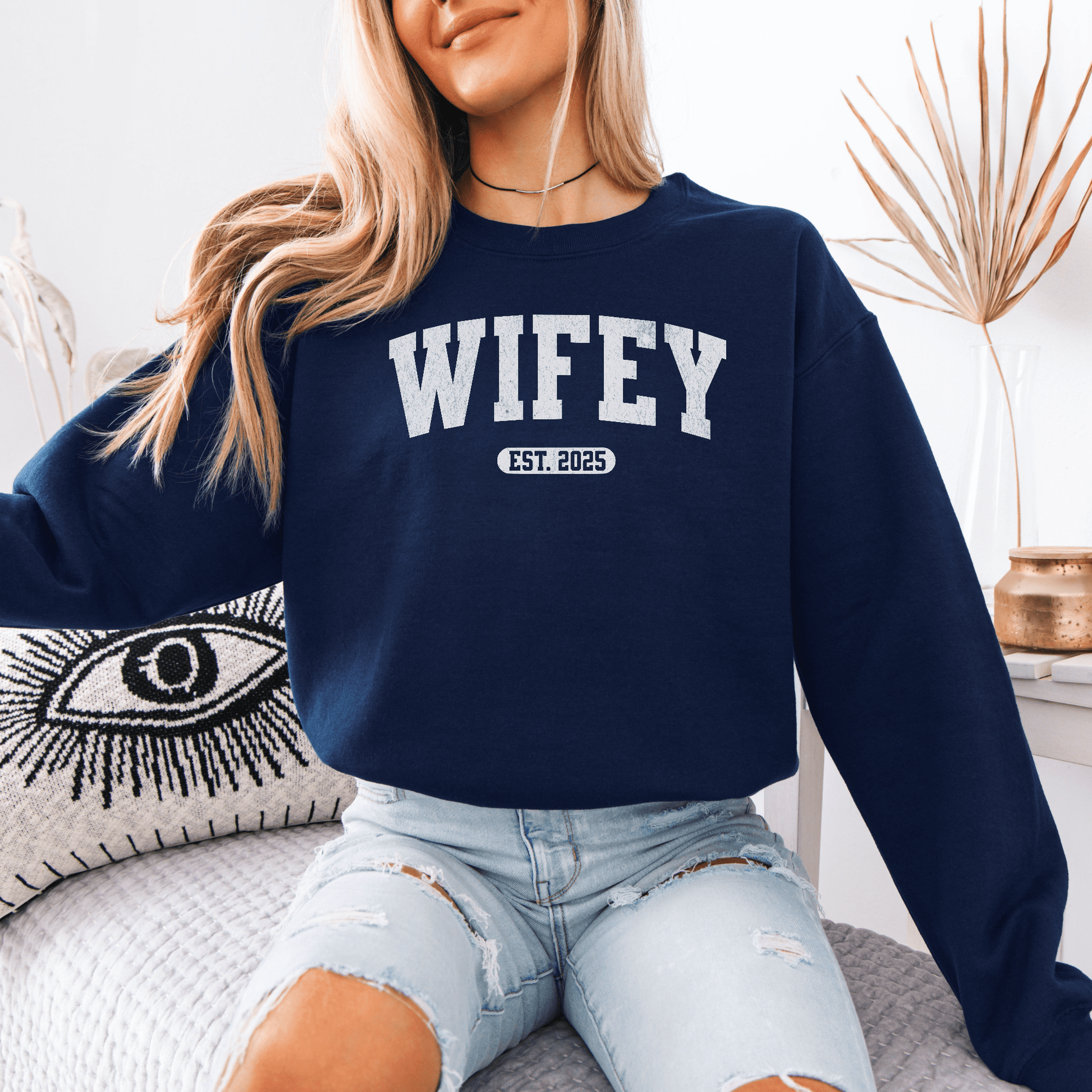Model wearing navy custom wifey sweatshirt with EST 2025 collegiate print paired with ripped jeans