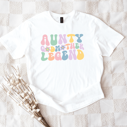 White t shirt with pastel groovy print reading aunty godmother legend shirt laid flat with dried flowers
