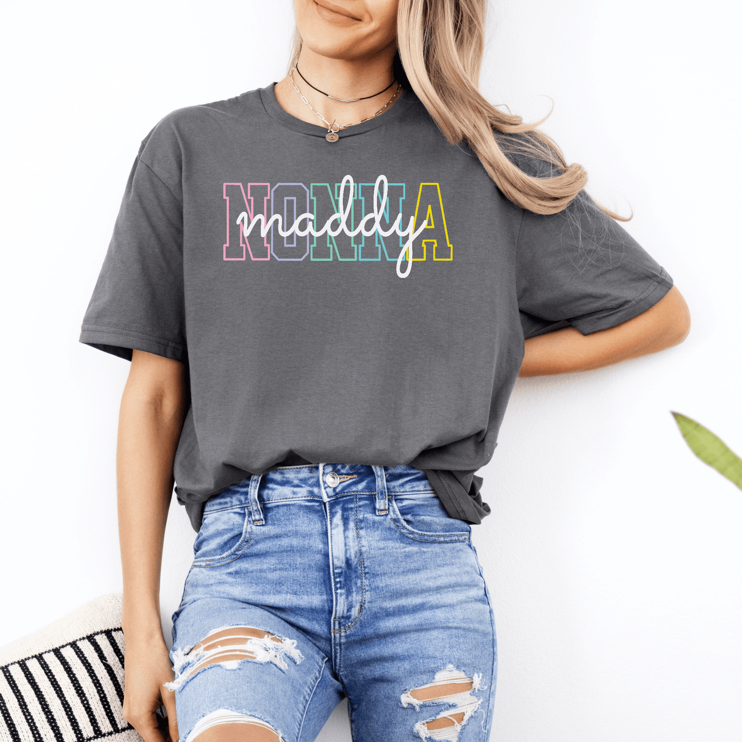 Smiling woman wearing a charcoal gray Custom Nonna Shirt with multicolor collegiate letters and cursive maddy logo