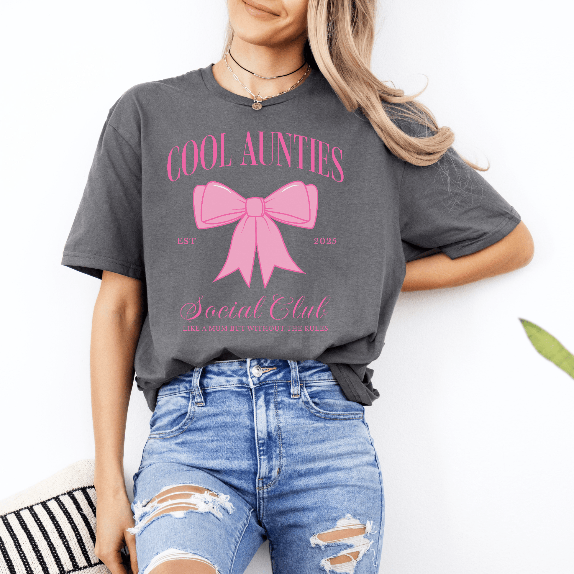 Woman wearing Custom Cool Aunties Club Shirt gray tee with pink bow graphic styled with ripped jeans
