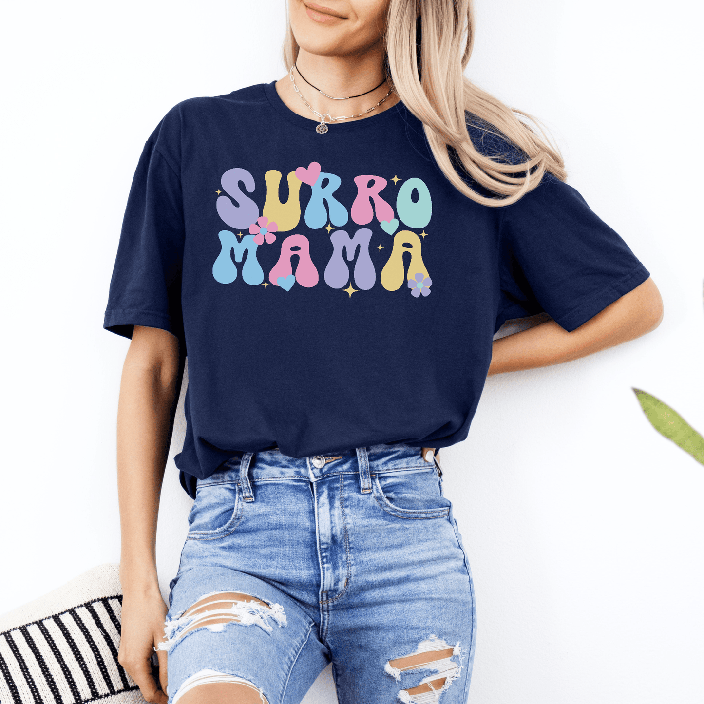 Woman wearing navy Cute Surrogate Mama Shirt with pastel retro floral lettering paired with ripped jeans