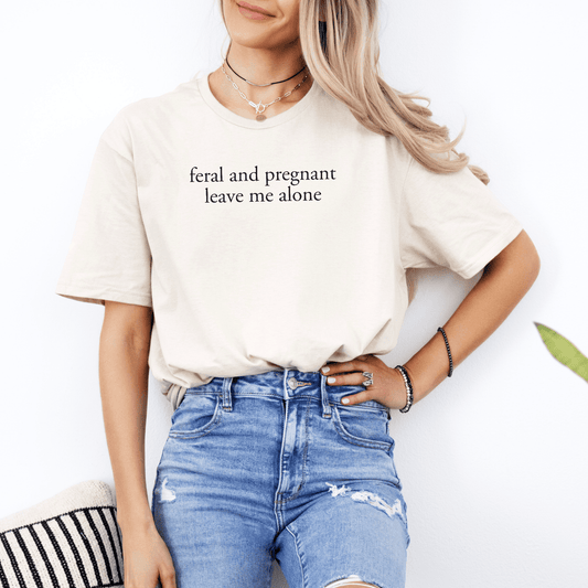 Funny Pregnancy Tee for Mums-to-Be. Beige maternity shirt reading feral and pregnant leave me alone modeled with jeans