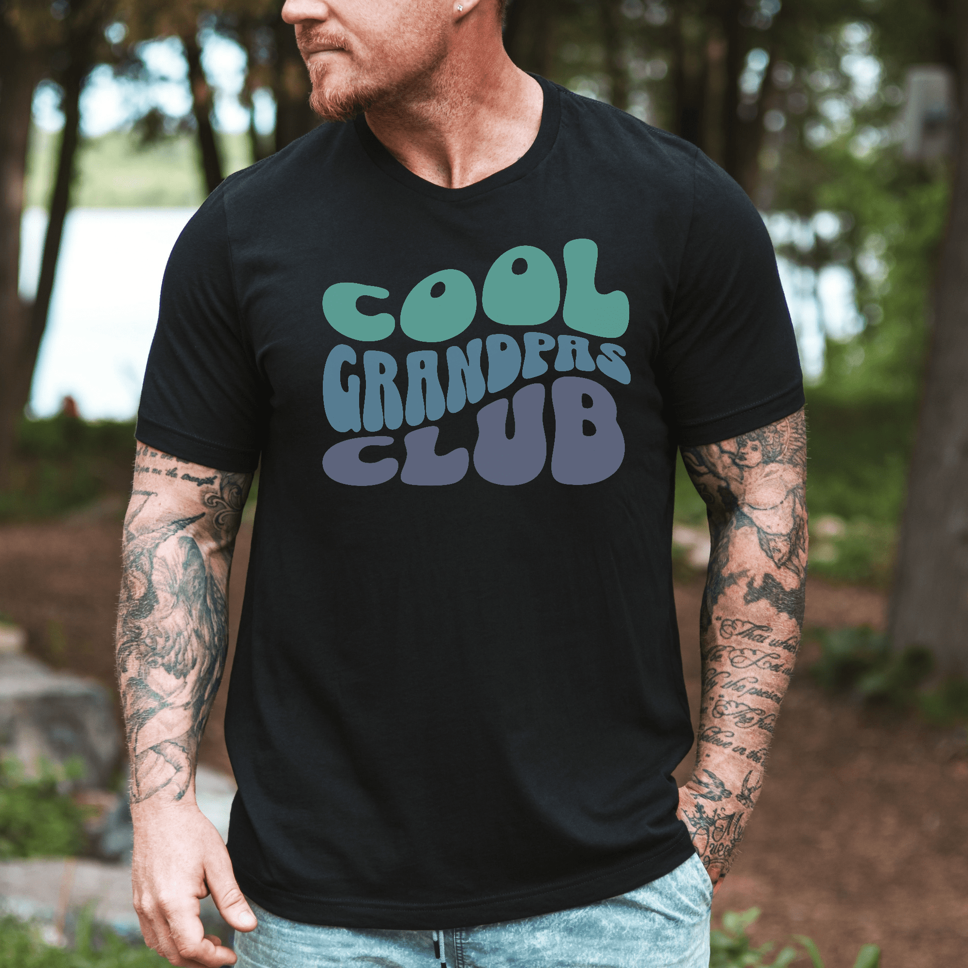 Man outdoors wearing black tee with teal and blue Cool Grandpas Club T-Shirt . design by Maddy and George Designs