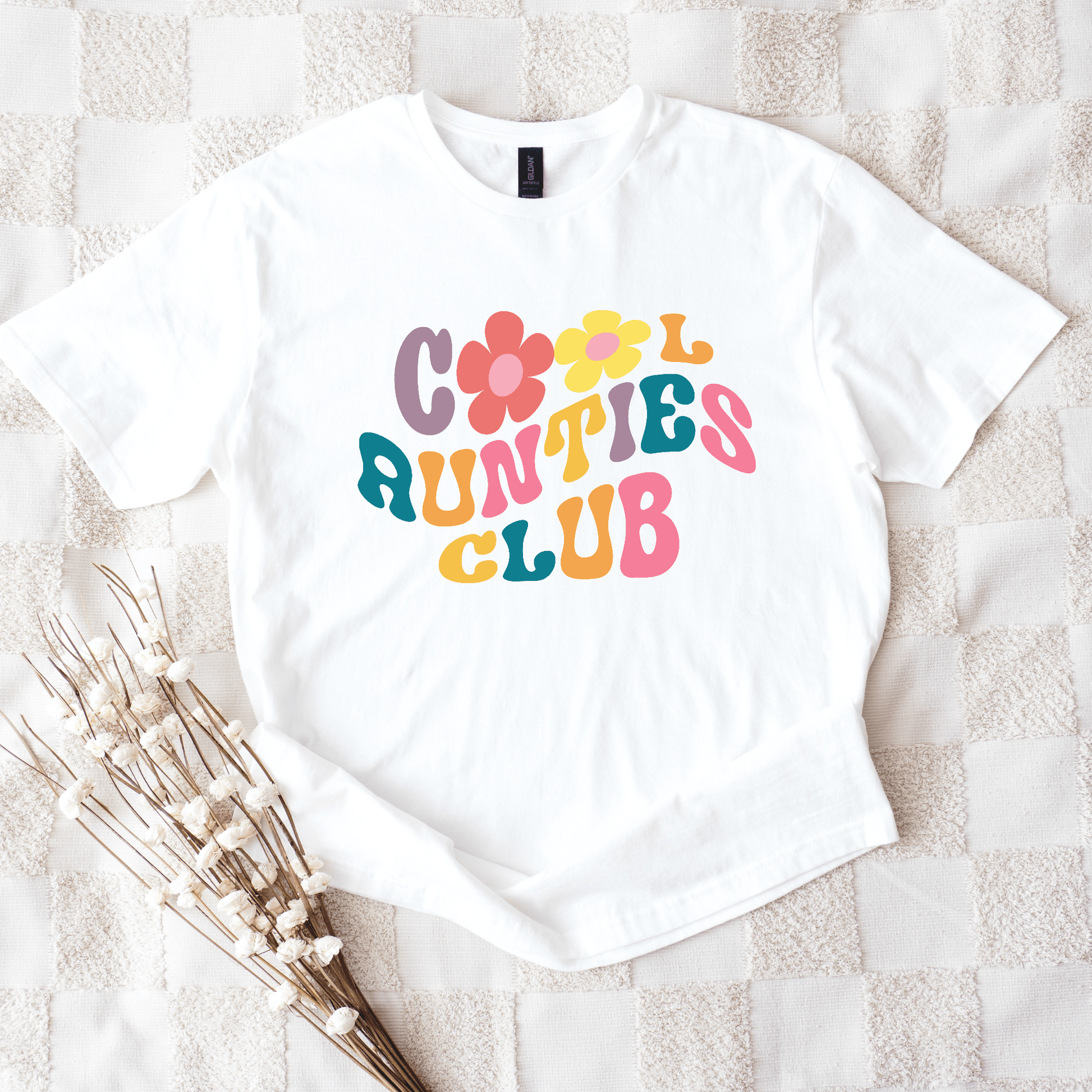 White tee displaying Retro Cool Aunties Club design with colorful 70s style lettering and floral graphics