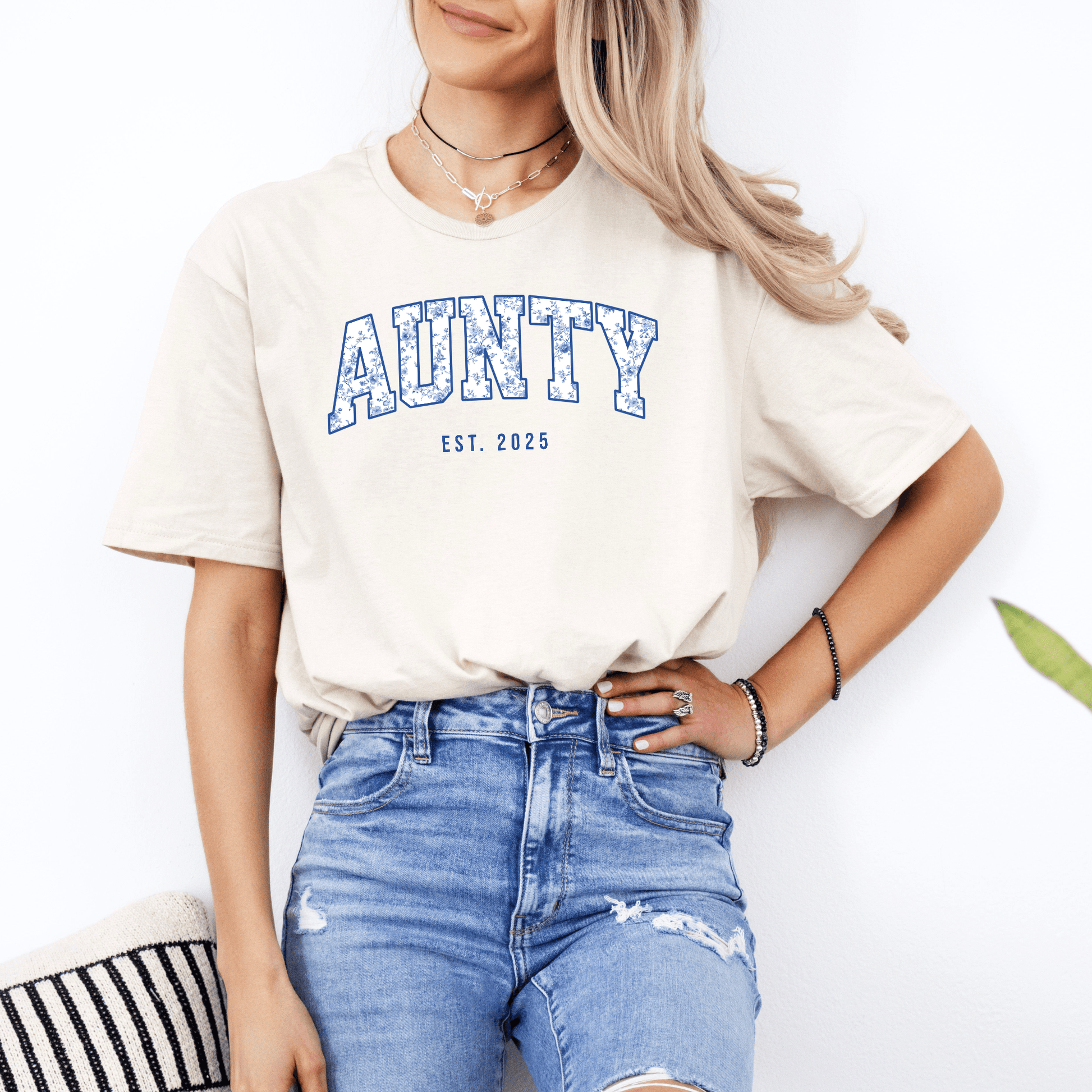 Woman wearing Maddy and George Designs Custom Aunty Est. Year Shirt cream tee with blue collegiate AUNTY print