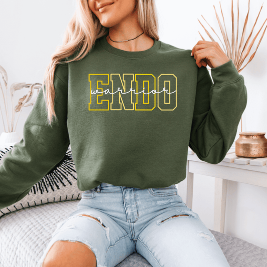 Woman wearing olive green Endometriosis Warrior Sweatshirt . with bold yellow ENDO print and ripped jeans