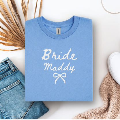 Custom Bride T-Shirt light blue folded tee with white handwritten Bride Maddy print and bow