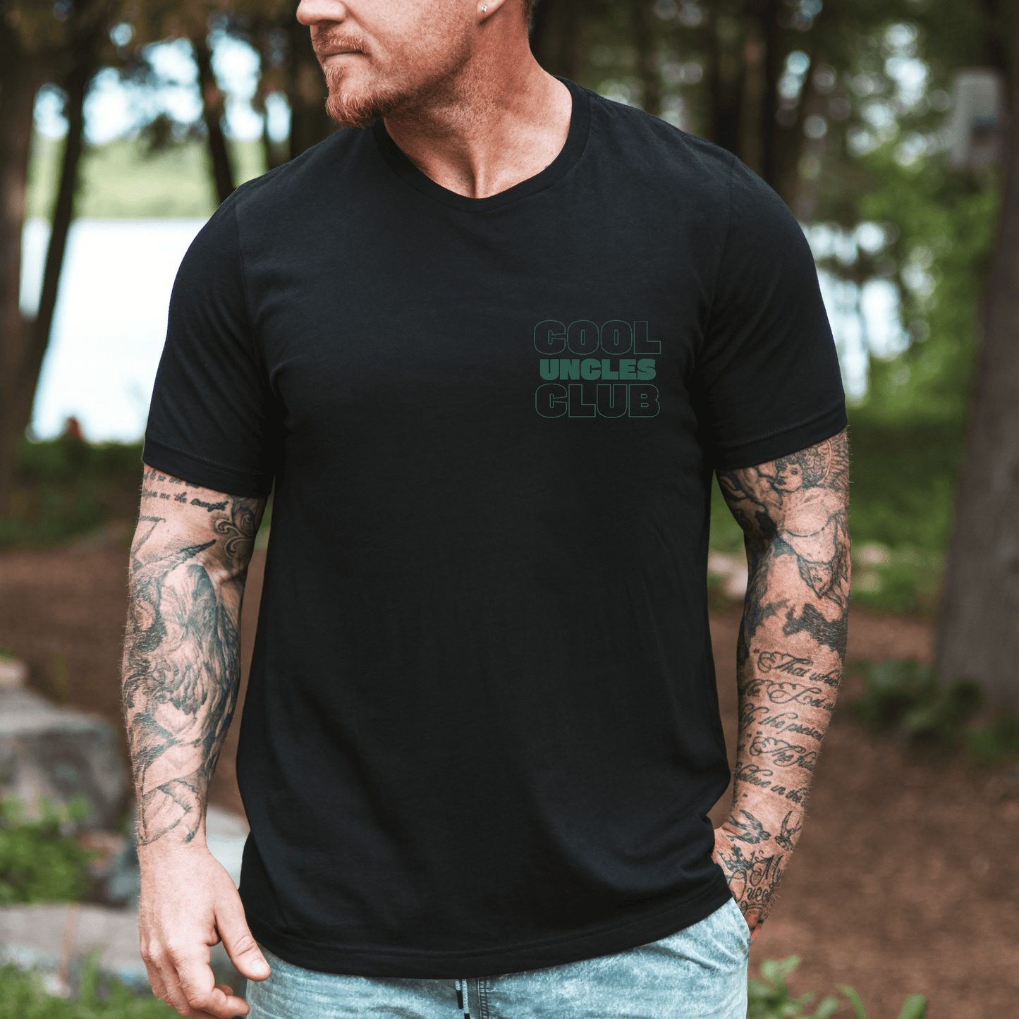 Tattooed man wearing Maddy and George Designs black tee with small Cool Uncles Club chest logo cool uncle shirt