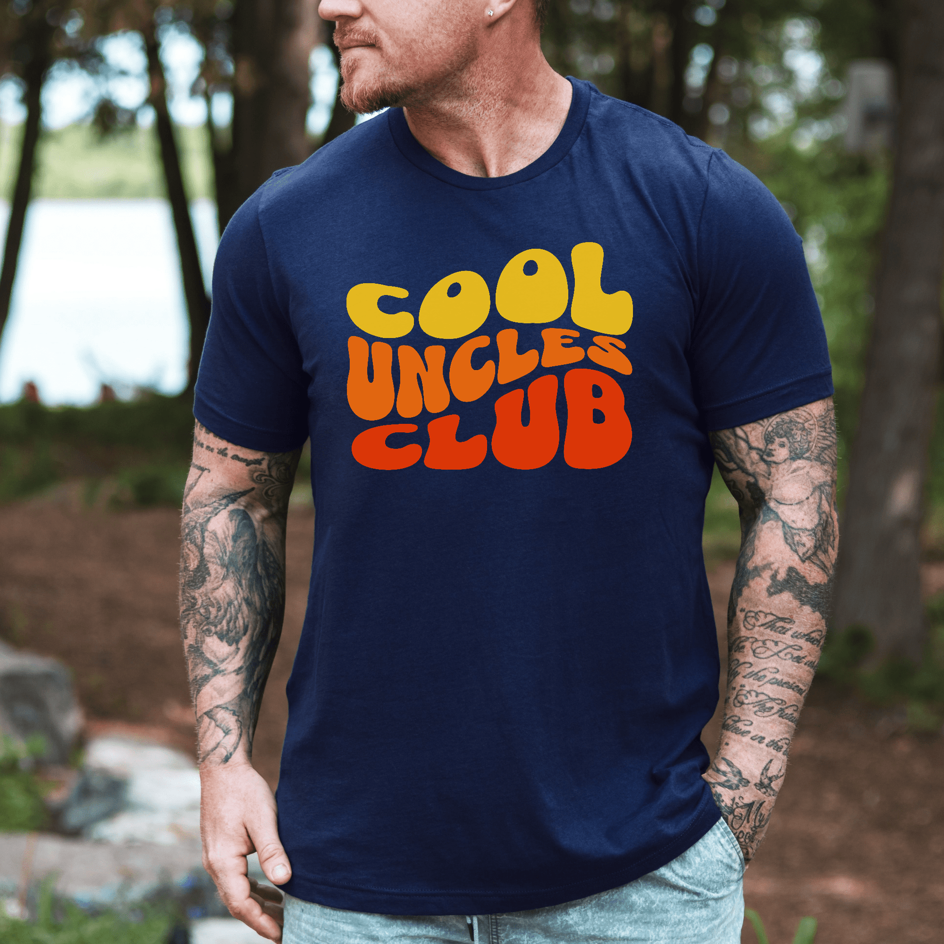 Maddy and George Designs Cool Uncles Club Shirt navy tee with retro yellow and orange logo worn by tattooed man