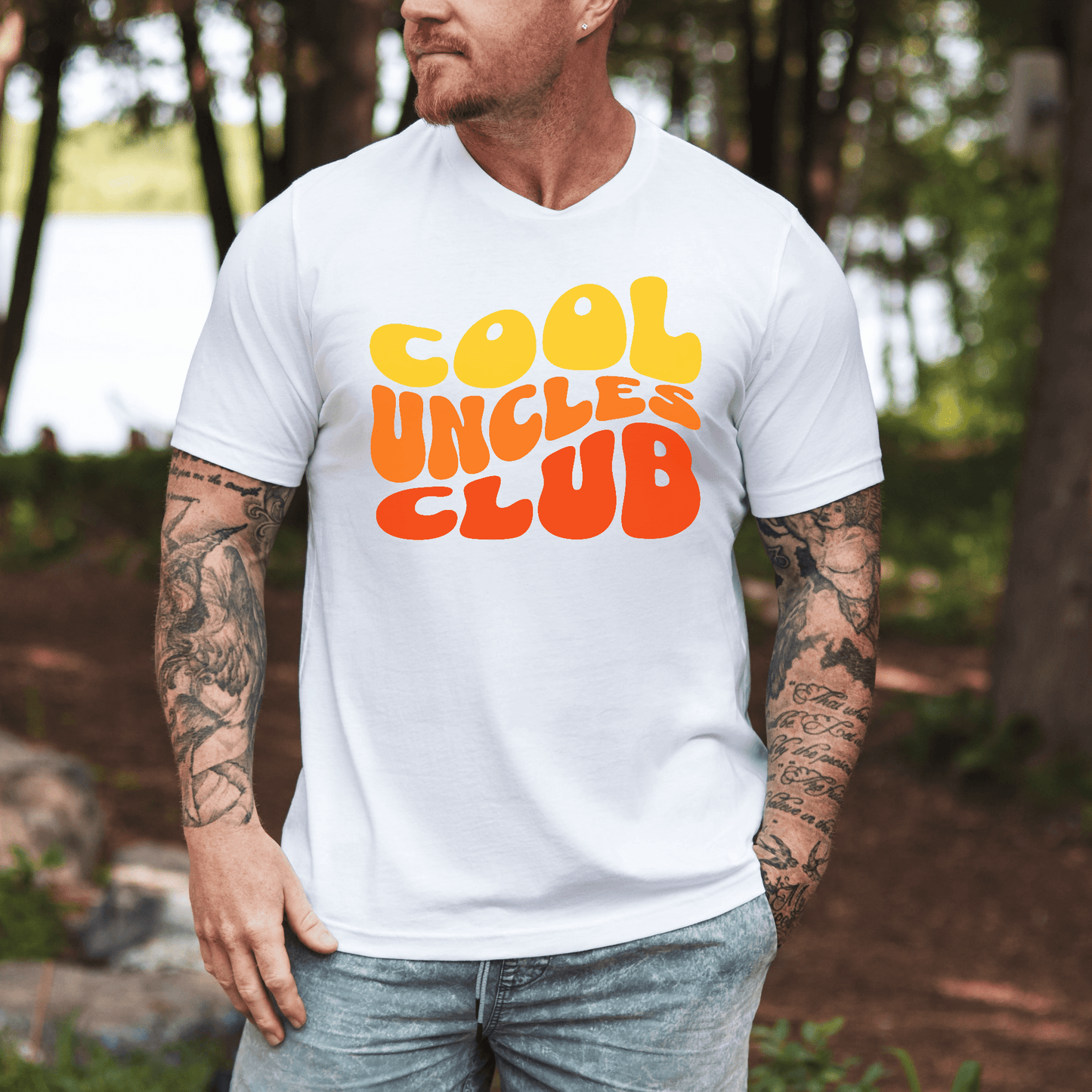 Tattooed man wearing Maddy and George Designs Cool Uncles Club Shirt white tee with retro yellow orange text