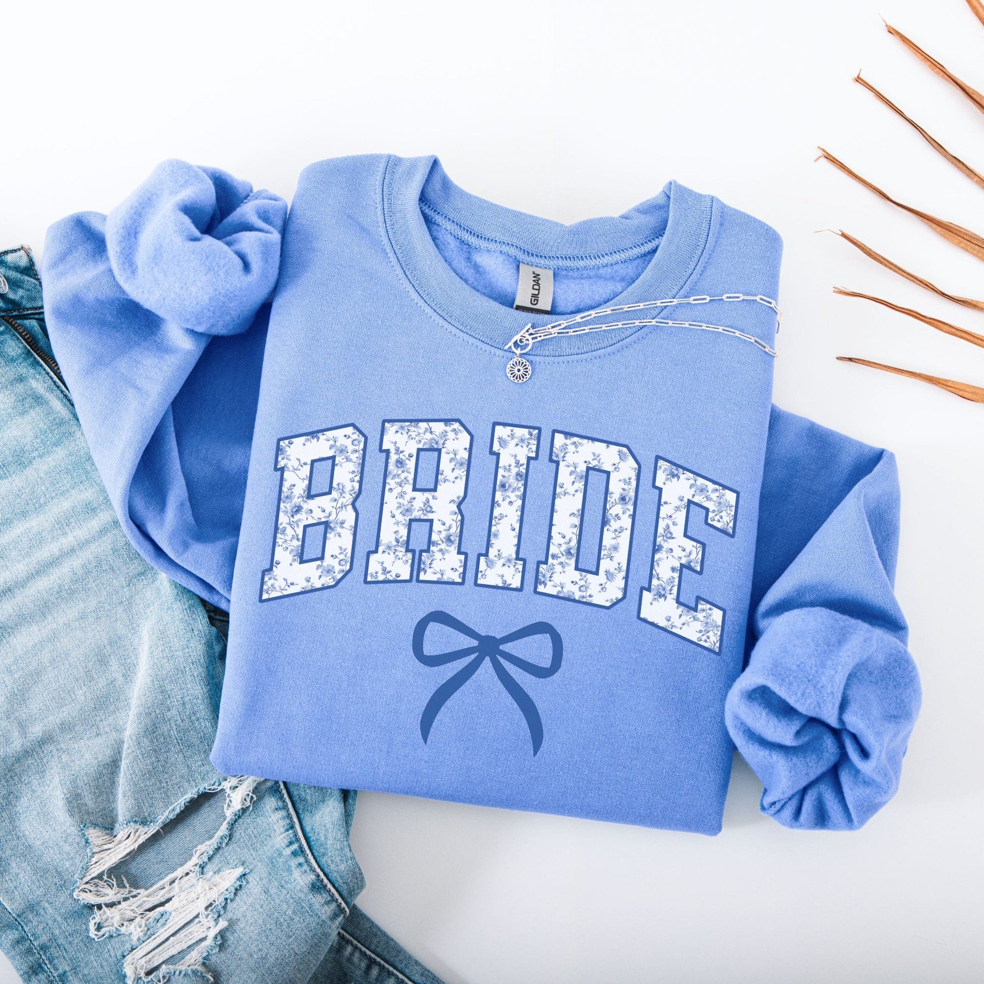 Chinoiserie Bride Sweatshirt folded light blue crewneck with floral BRIDE lettering and bow