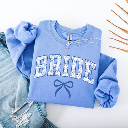 Chinoiserie Bride Sweatshirt folded light blue crewneck with floral BRIDE lettering and bow